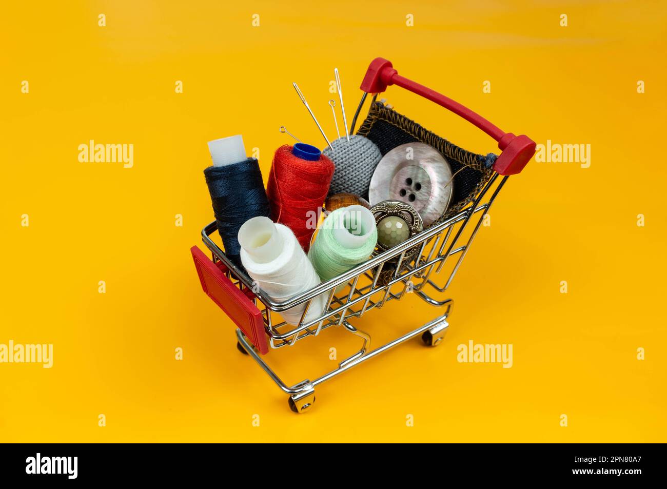A shopping basket with threads and buttons. Next to thimbles and tools