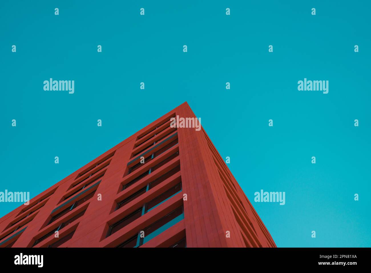 A vibrant red highrise building stands in stark contrast to a