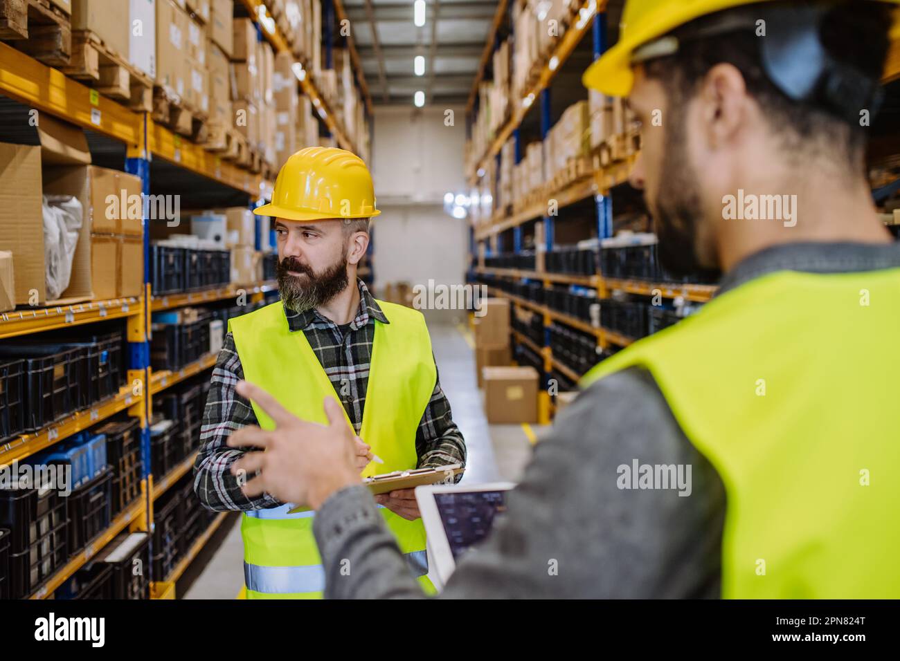 Warehouse workers checking stuff in warehouse with digital system in tablet. Stock Photo