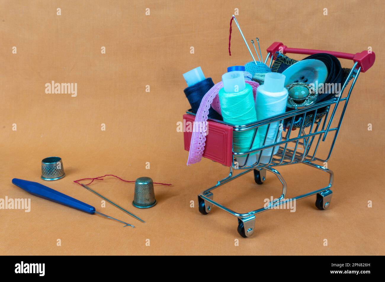 A shopping basket with threads and buttons. Next to thimbles and tools
