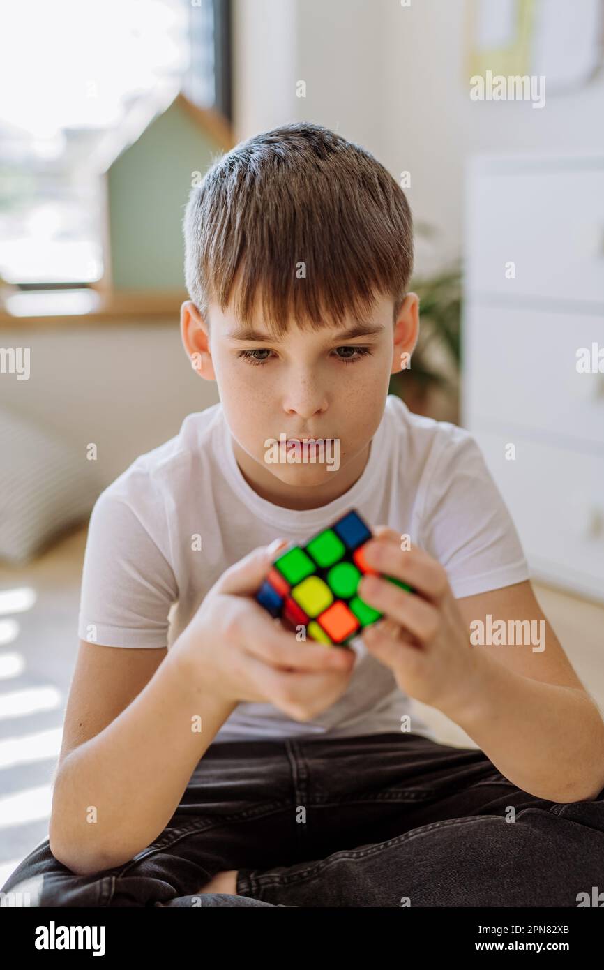 Little boy playing with Rubiks cube in his room. Stock Photo