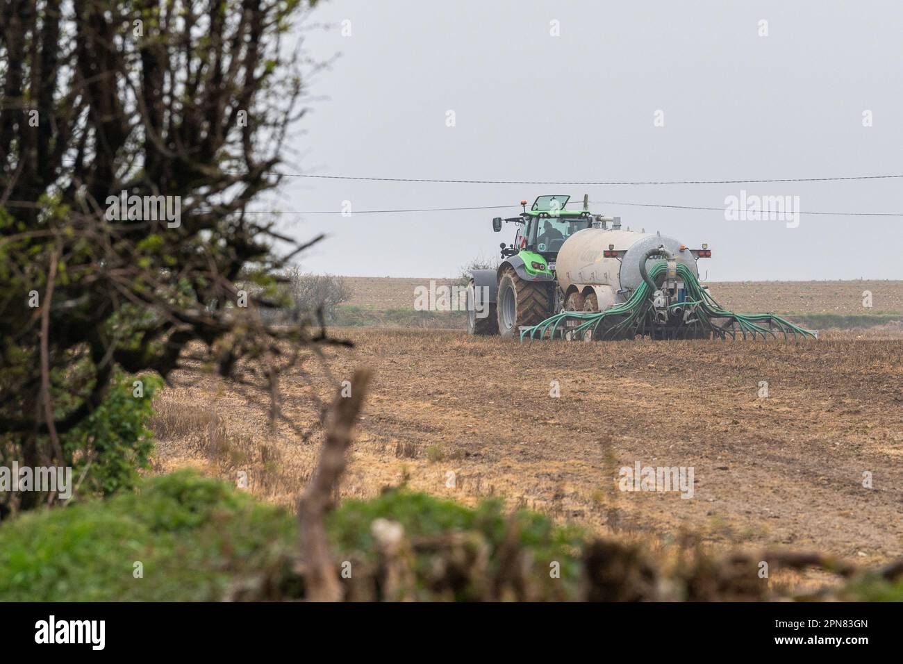 Ballynascubbig, West Cork, Ireland. 17th Apr, 2023. Farmer Liam Ryan, who farms pigs and dairy, spreads slurry on an 80 acre field using a Conor 3500 TR dribble bar spreader, being hauled by a Deutz-Fahr 7250 tractor at a rate of 3,000 litres per acre. Credit: AG News/Alamy Live News Stock Photo