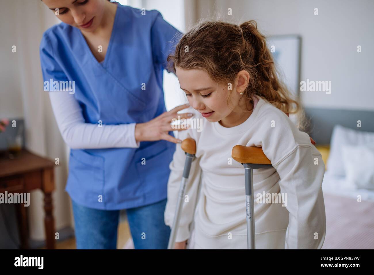 Young Nurse Helping To Walk To Little Girl With Broken Leg Stock Photo