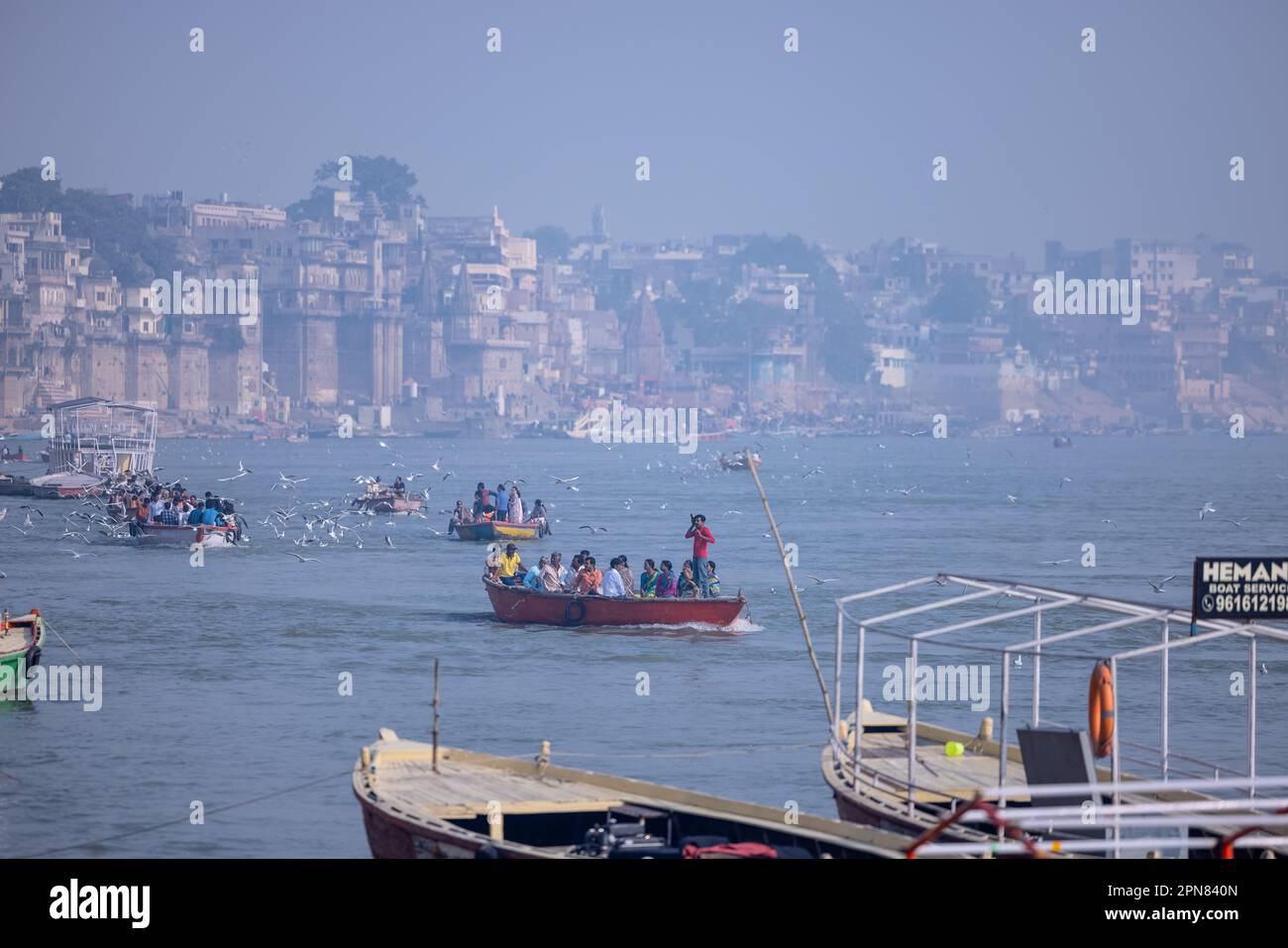 Varanasi, Uttar Pradesh, India - November 2022: Tourists enjoying boat ride in the river ganges along with the herd of sea gulls at varanasi. Stock Photo
