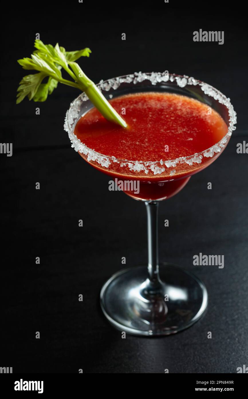 Bloody Mary cocktail with celery on a black background. The glass is