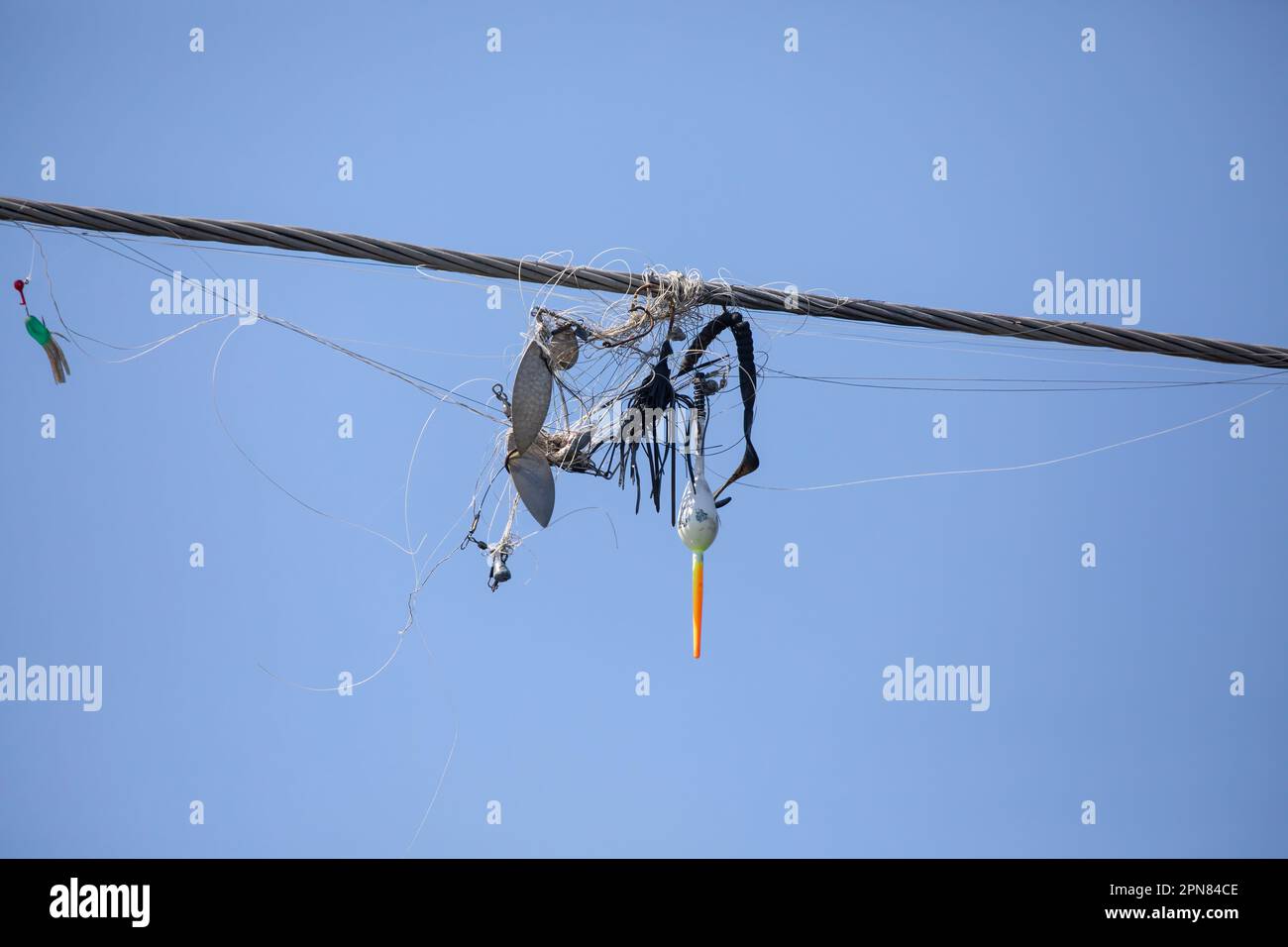 Tangled fishing line and lures wrapped around overhead wires against a