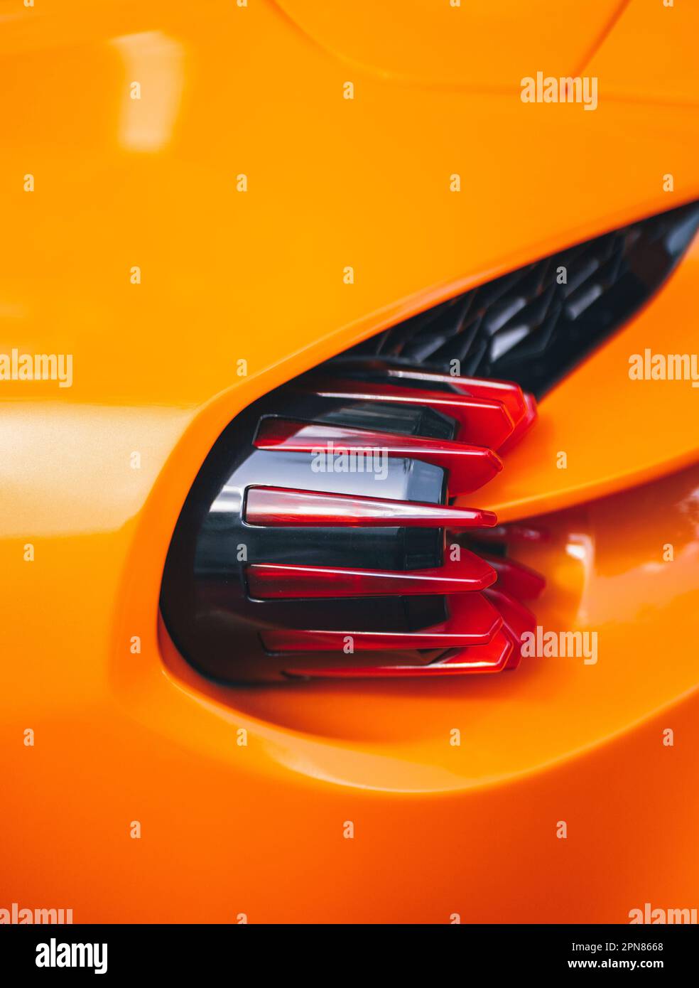 A vertical closeup shot of the cool design of a backlight on an orange sports car Stock Photo