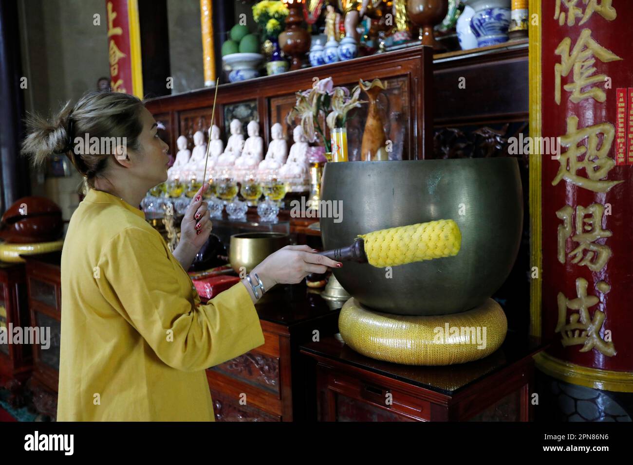 Rong Thanh Temple. Vietnamese buddhist woman using a giant singing bowl