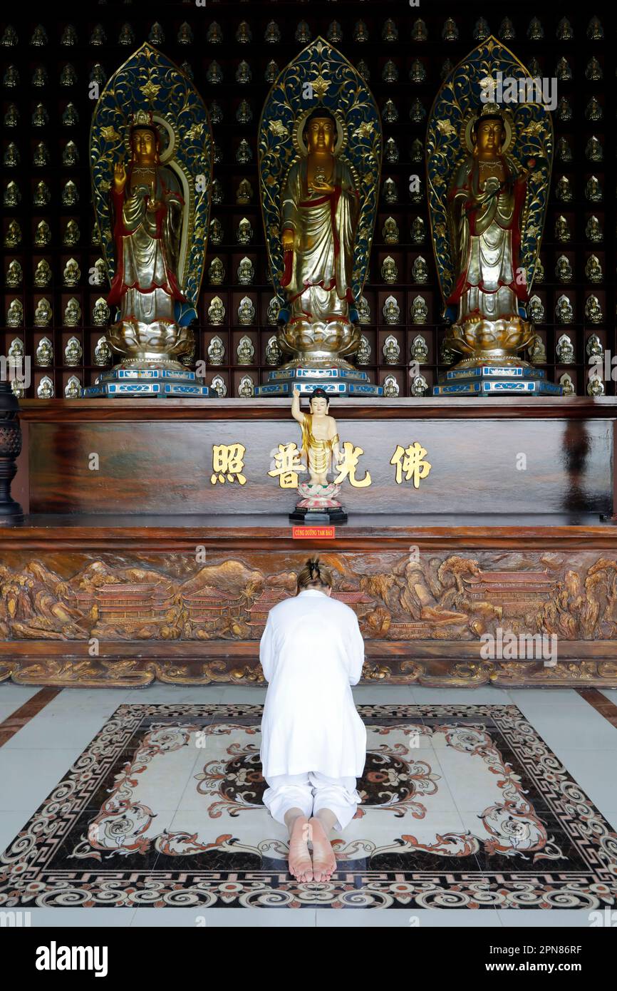 Phat Quang Buddhist temple. Woman worshipper kneeling in prayer and
