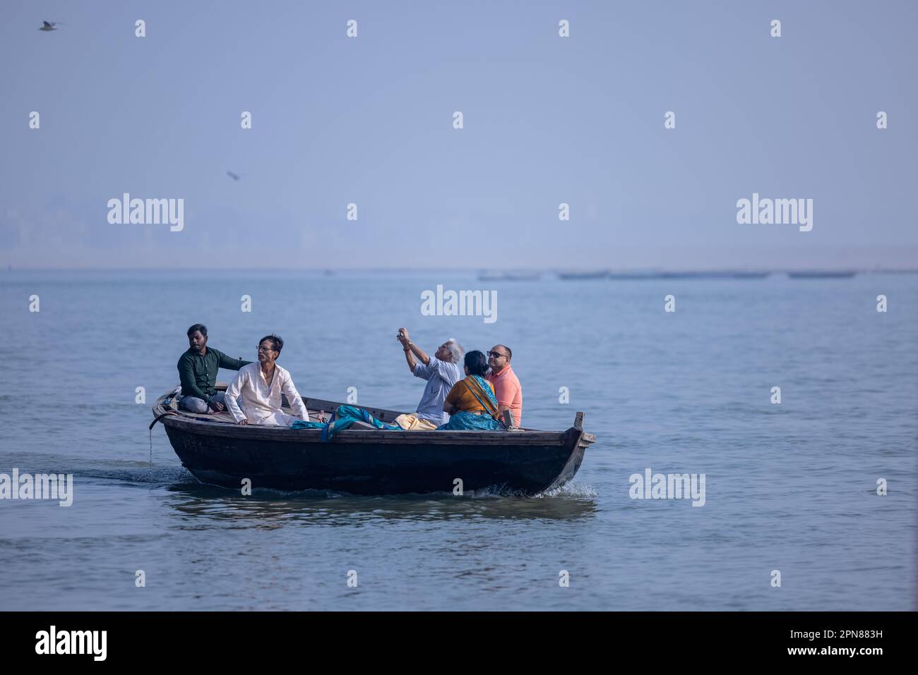 Varanasi, Uttar Pradesh, India - November 2022: Tourists enjoying boat ride in the river ganges along with the herd of sea gulls at varanasi. Stock Photo