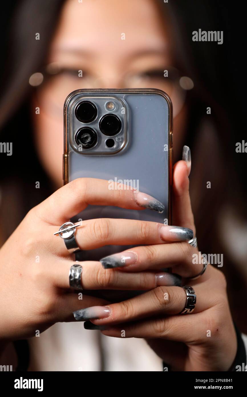 Female hand with smartphones close up. A young woman using mobile phone. Instagram, Tik Tok and Facebook. Stock Photo