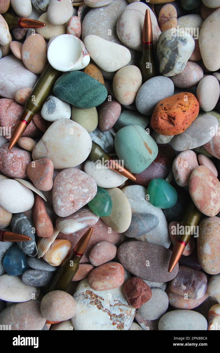 Parts of ammunition are visible from under the stones on the seashore vertical stock photo Stock Photo
