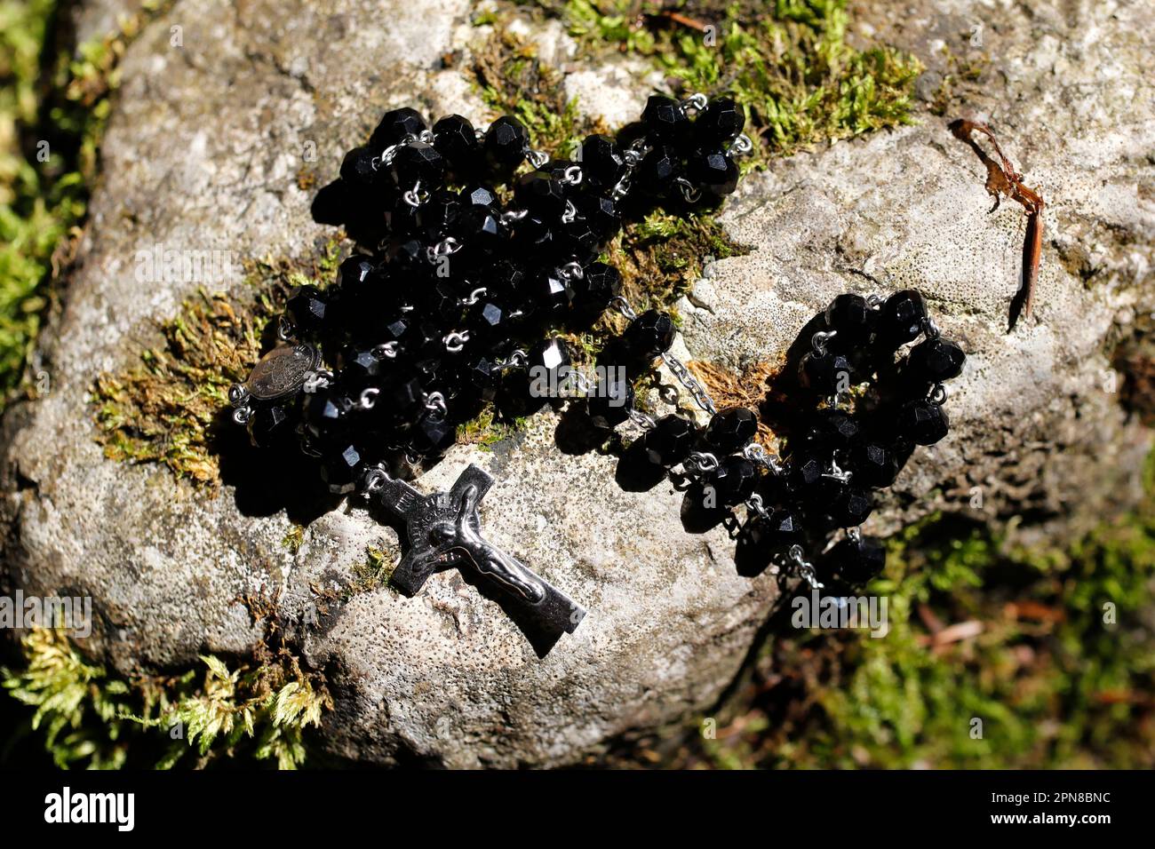 Black Rosary on an old stone with moss. France. Stock Photo
