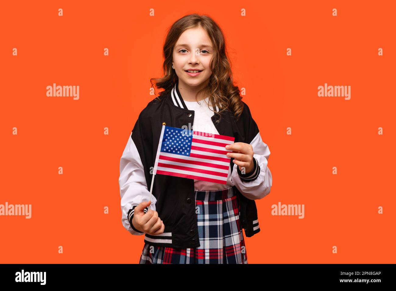 Girl wearing in school outfit and holds small national flag of the