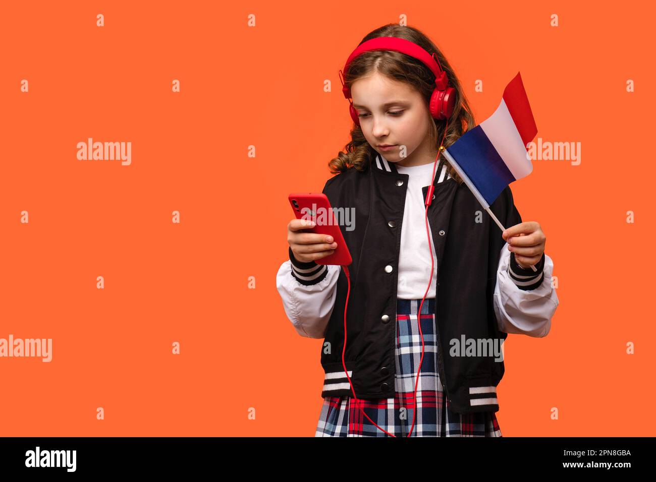 Teen school girl in casual clothes and headphones holds small national