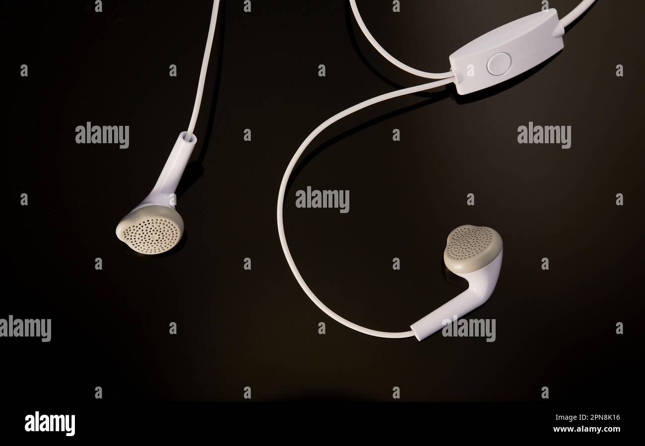Pair of cool white earphones isolated on a black background. Stock Photo