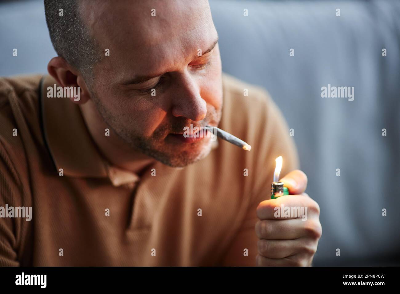 Adult man lighting up cigarette smoking at home for therapeutic purpose