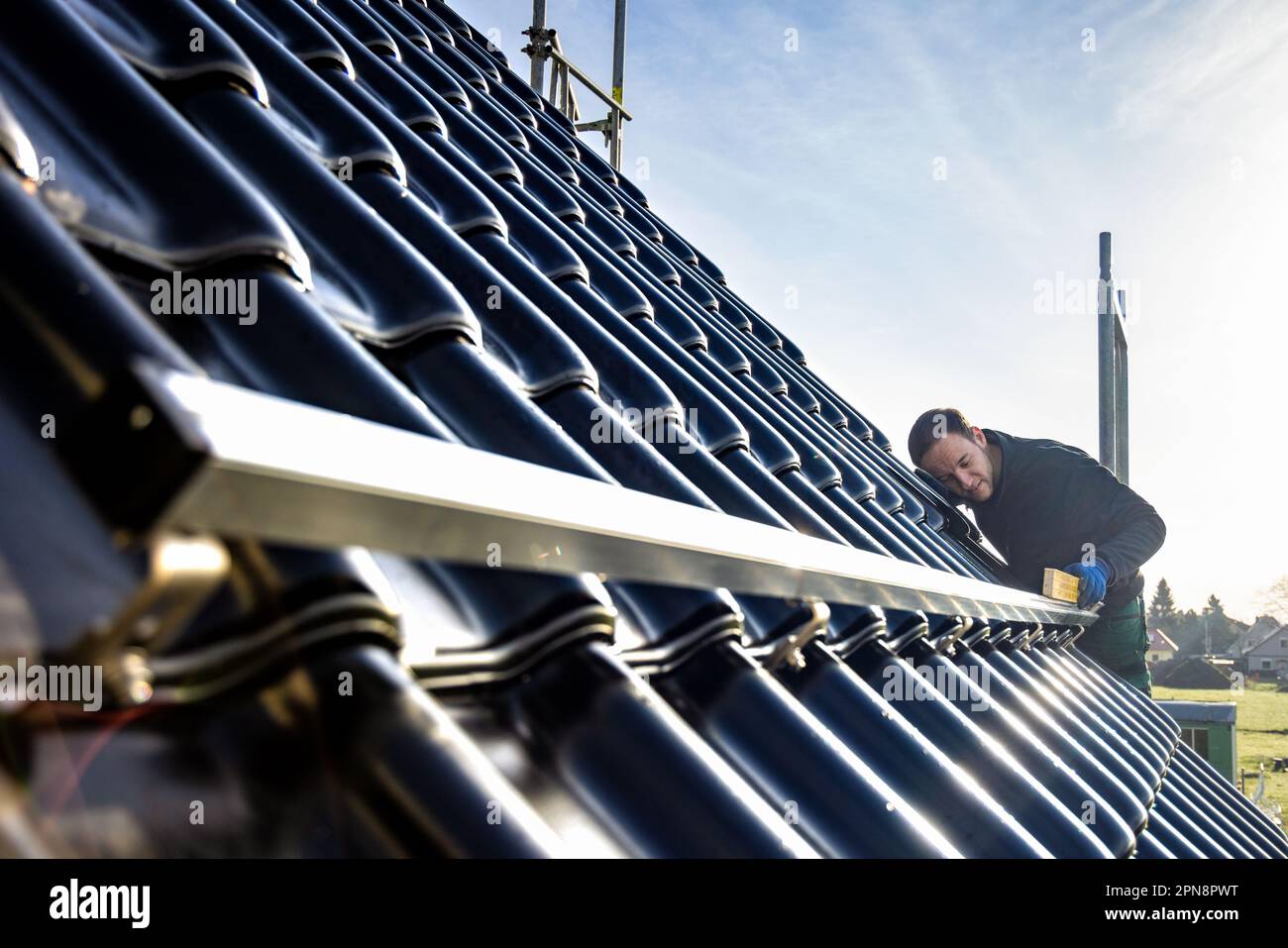 Craftsman installing a solar panel mounting rail on the roof of a single-family home Stock Photo
