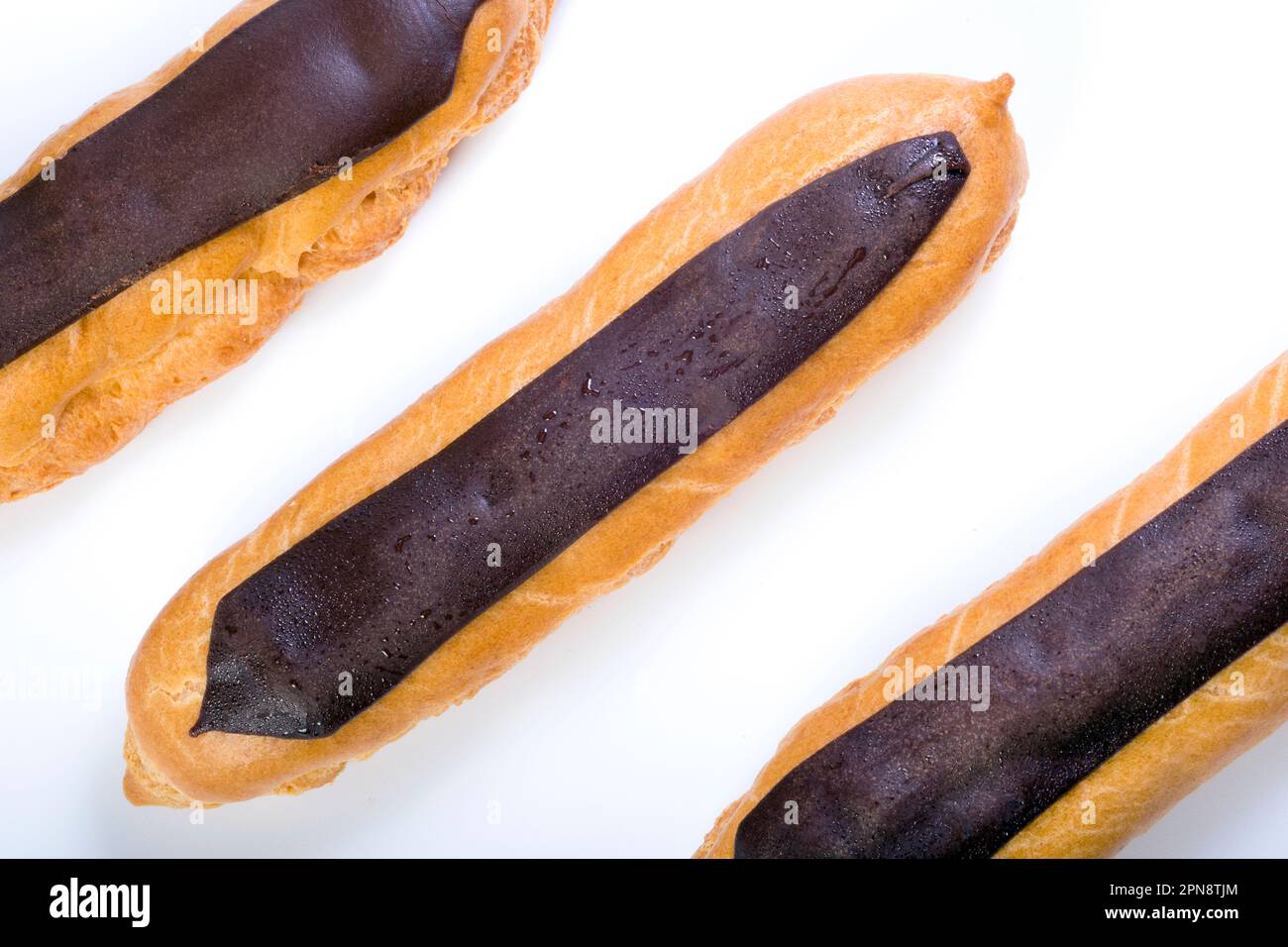 Fresh eclairs with custard inside on a white background. Top view Stock Photo