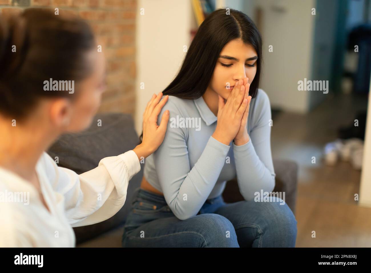 Female psychologist calming sad spanish lady, doctor consulting patient