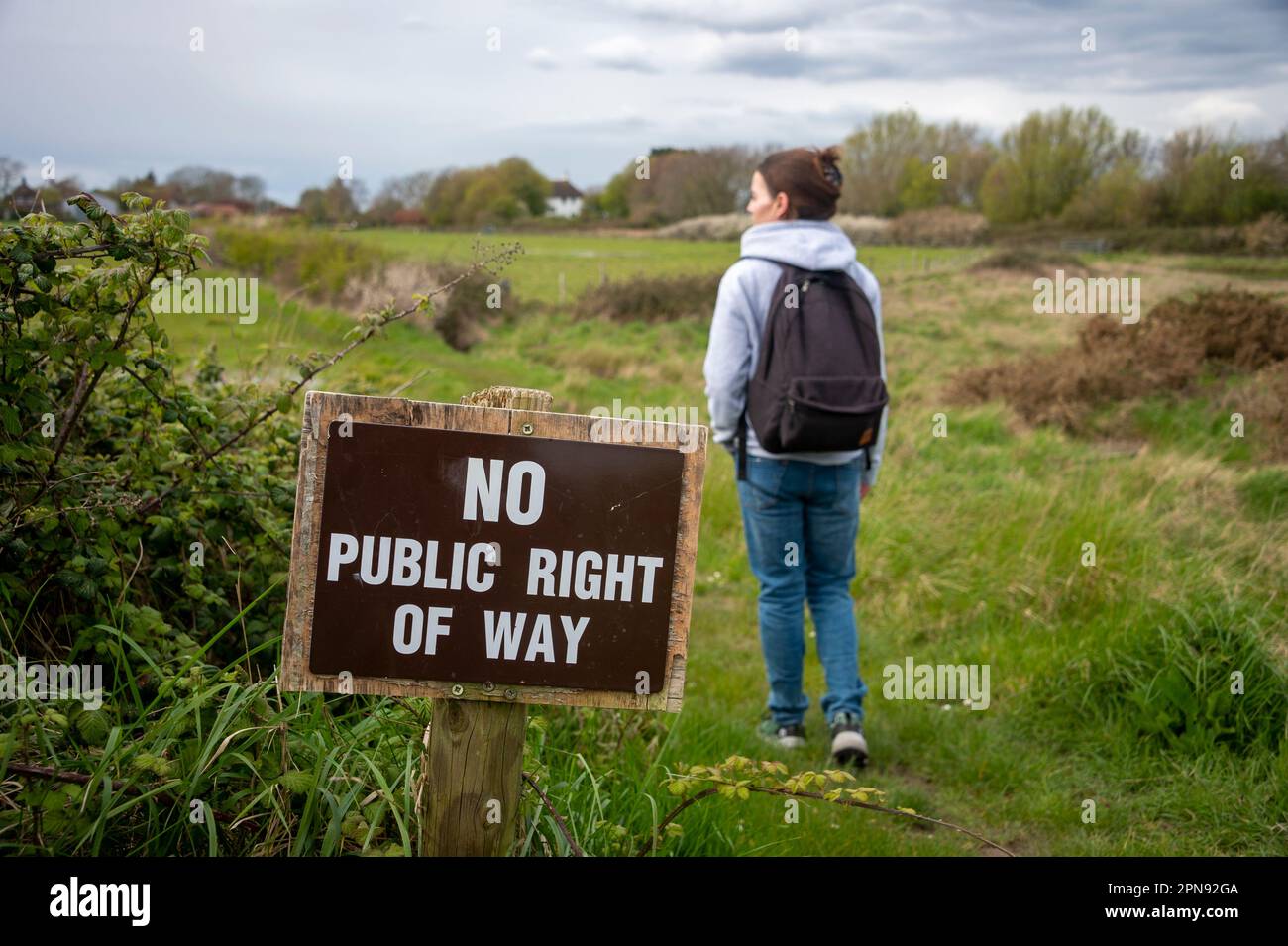 No right of way sign on a footpath with a female hiker. Right to roam concept. Stock Photo