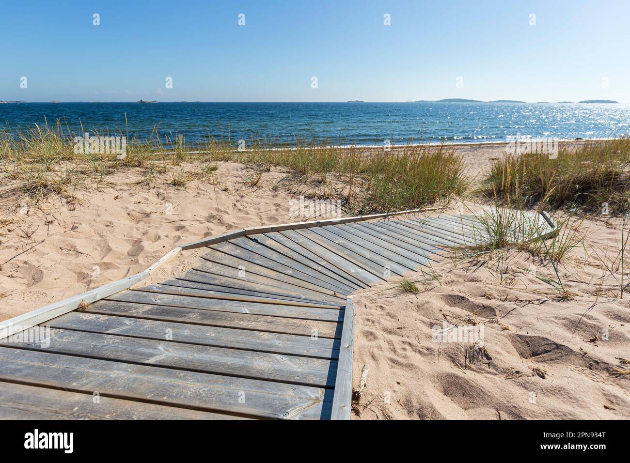 Wooden boardwalk leading to an empty beach in Hanko, Finland, on a sunny day in the summer. Stock Photo
