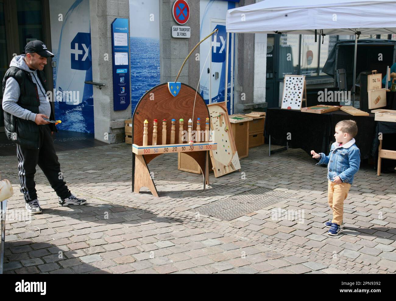 A young boy playing skittles in the town centre, Domfront en Poiraie, Normandy, France, Europe Stock Photo