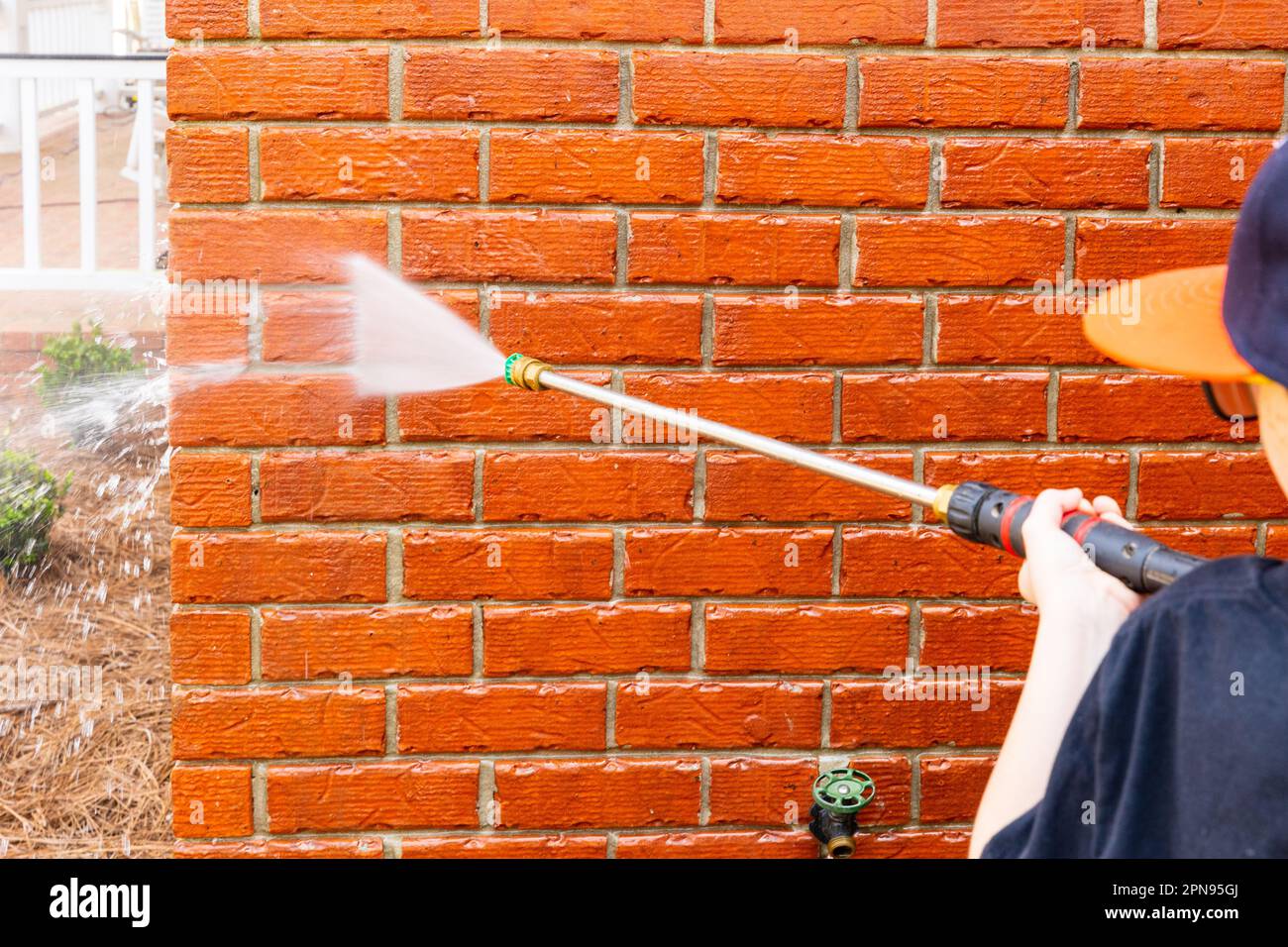 Brick wall being cleaned with water from pressure washer Stock Photo