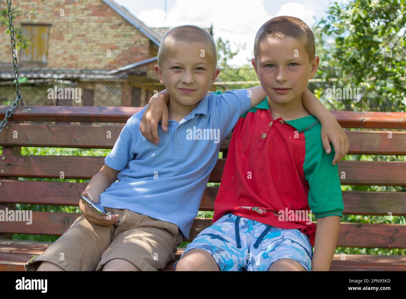 two brothers hugged sitting on the bench Stock Photo Alamy