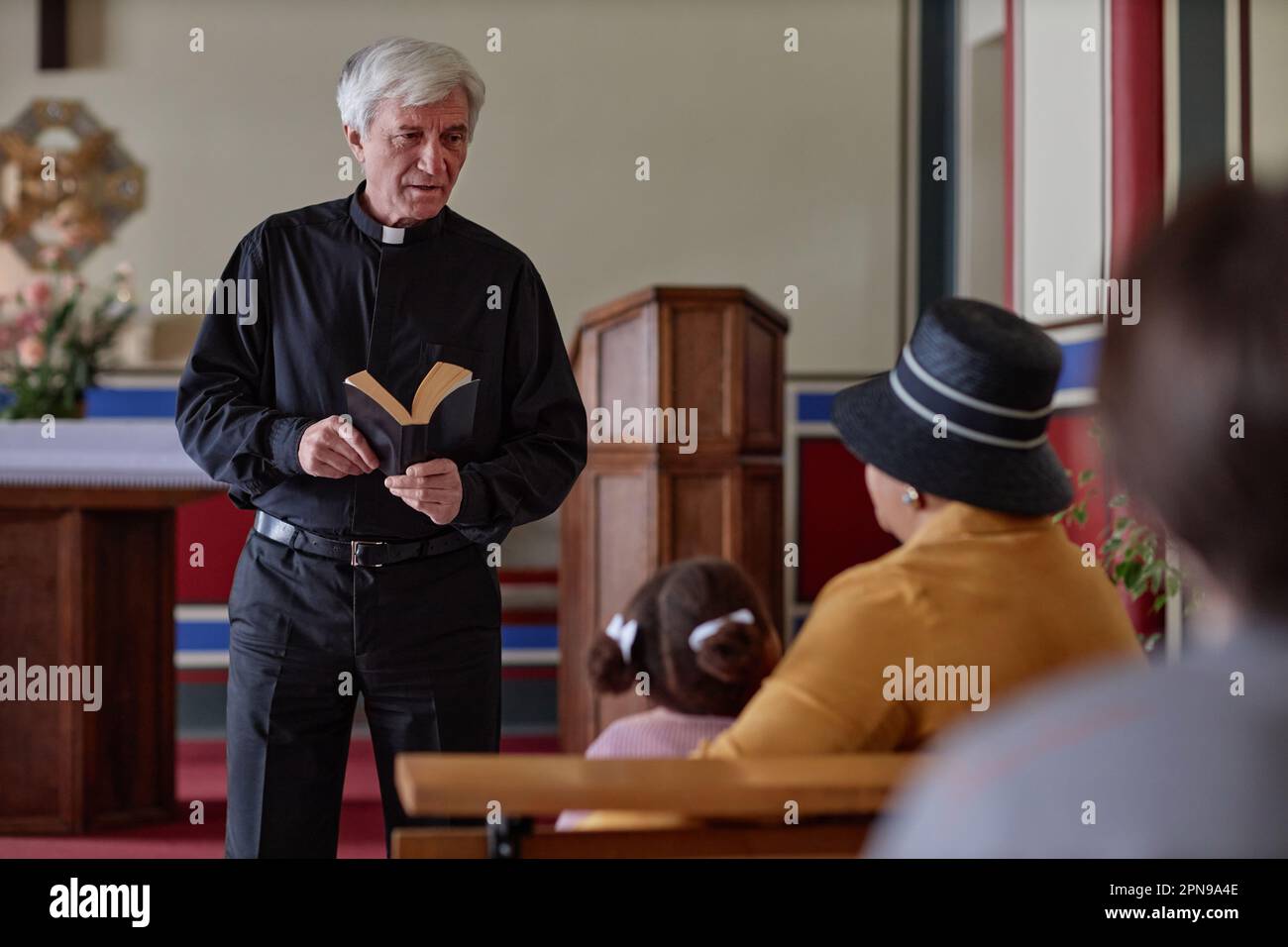 Senior priest standing with Bible reading sermon for people in the