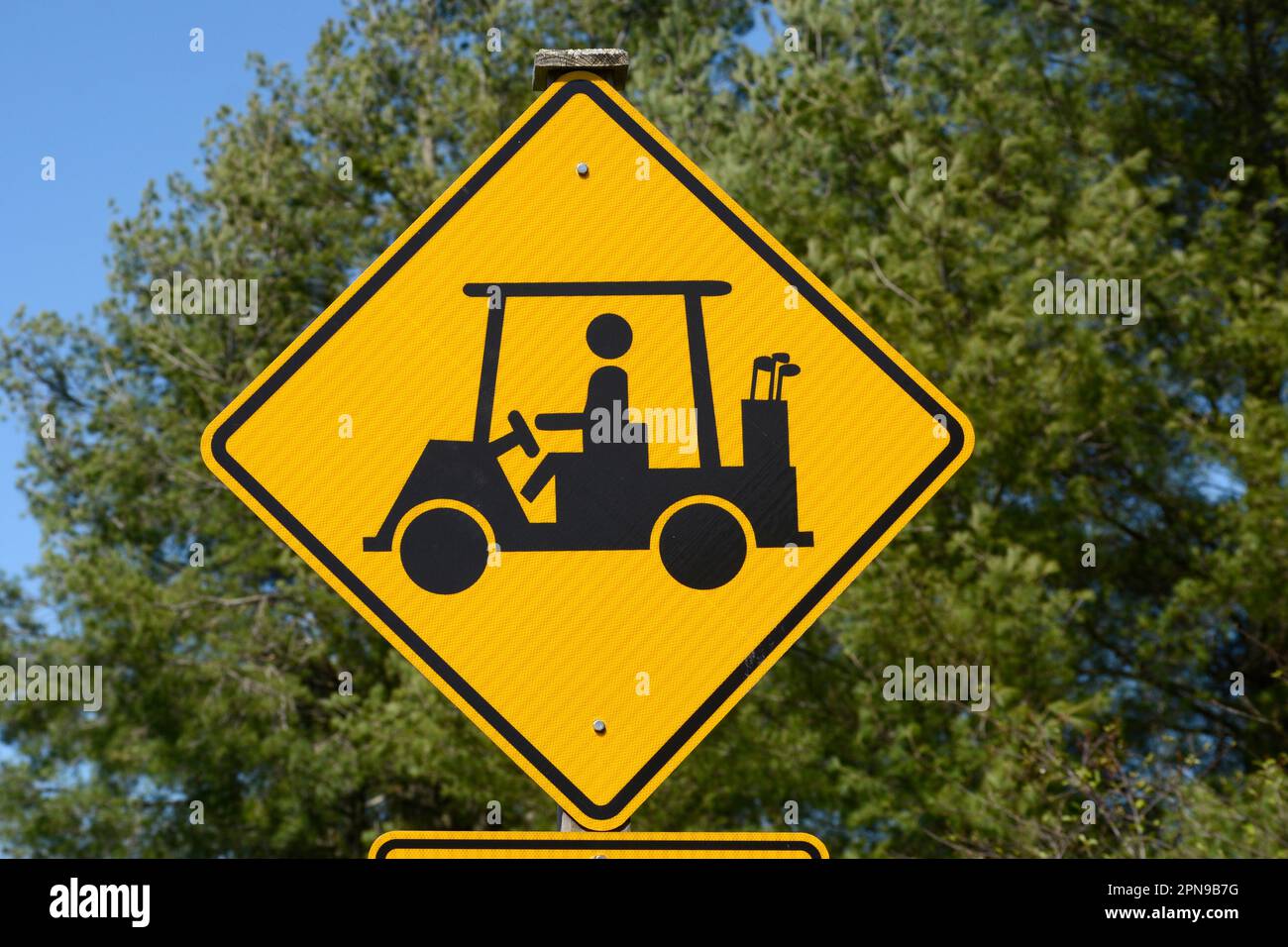 A golf cart crossing sign along a road warns motorists to watch for golfers and golf carts crossing the road in Abingdon, Virginia. Stock Photo