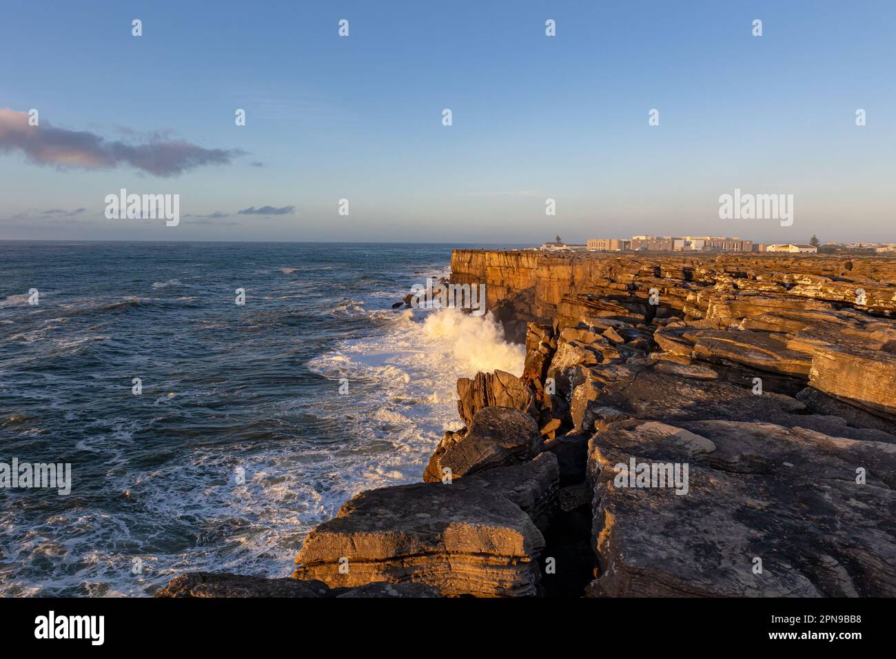 Sea waves crash against a rocky cliff at golden hour Stock Photo - Alamy