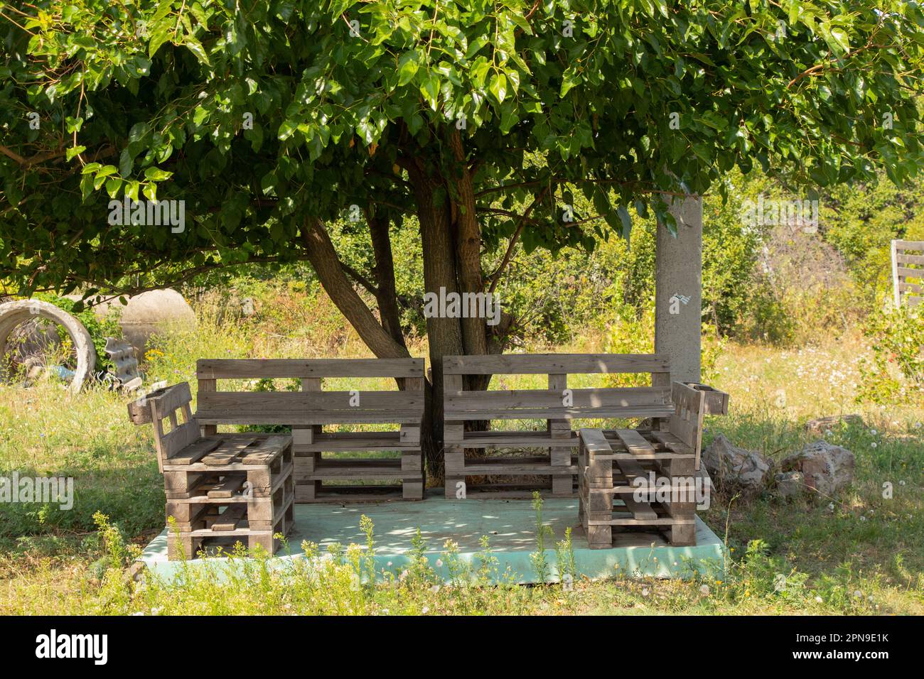 pallet table and chairs stand in the garden under a tree, pallet furniture, manual robot Stock Photo