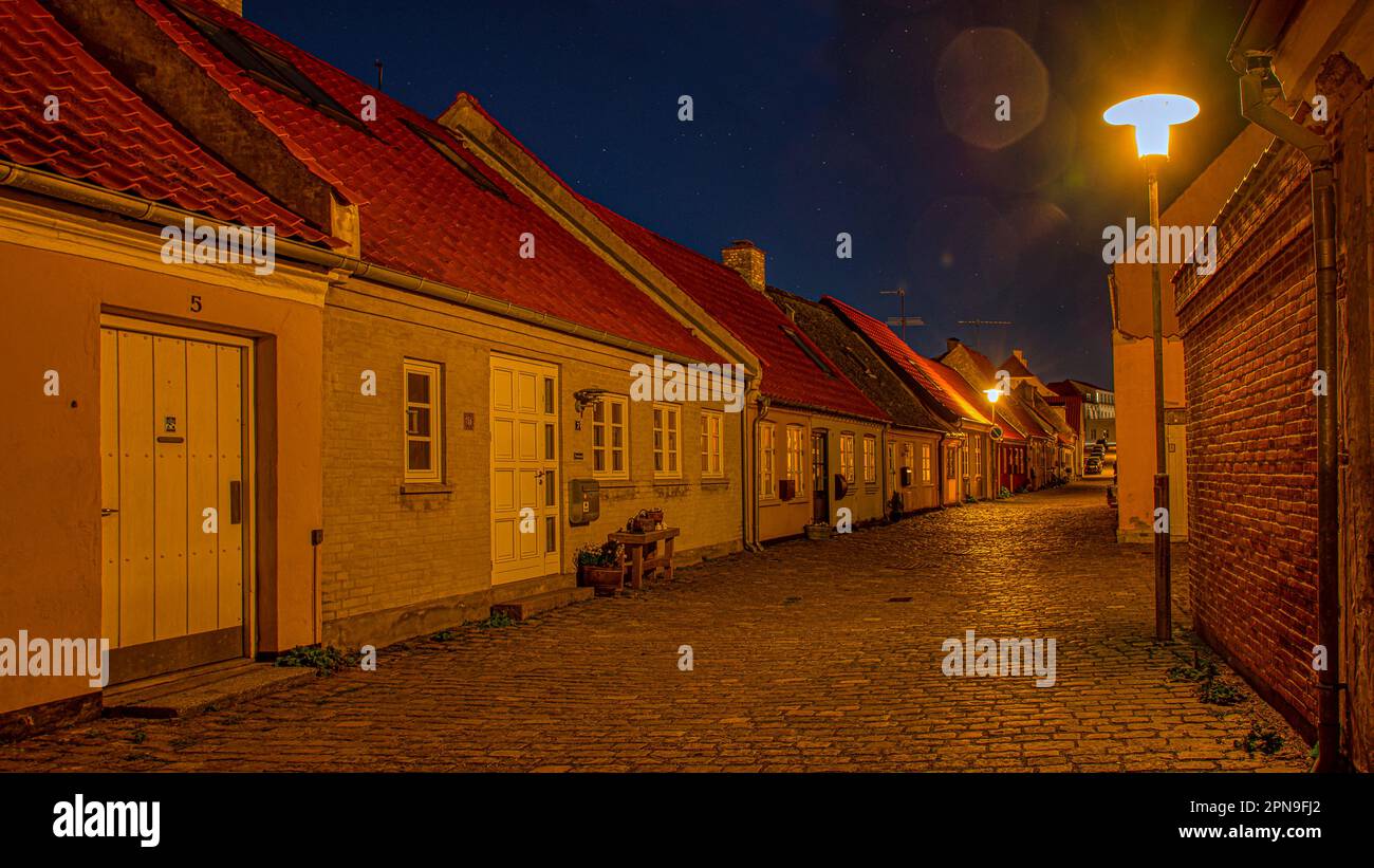 the illuminated cobblestone street Strandstræde during the twilight hour, Kaulundborg, Denmark, April 4, 2023 Stock Photo