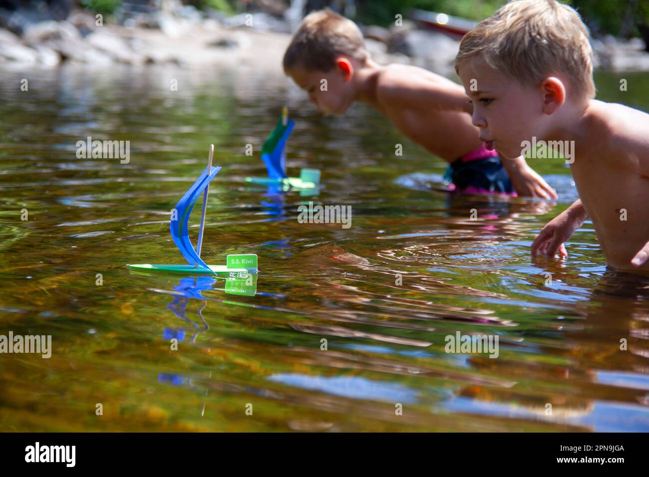 Two young boys with homemade toy sailboats in lake Stock Photo Alamy