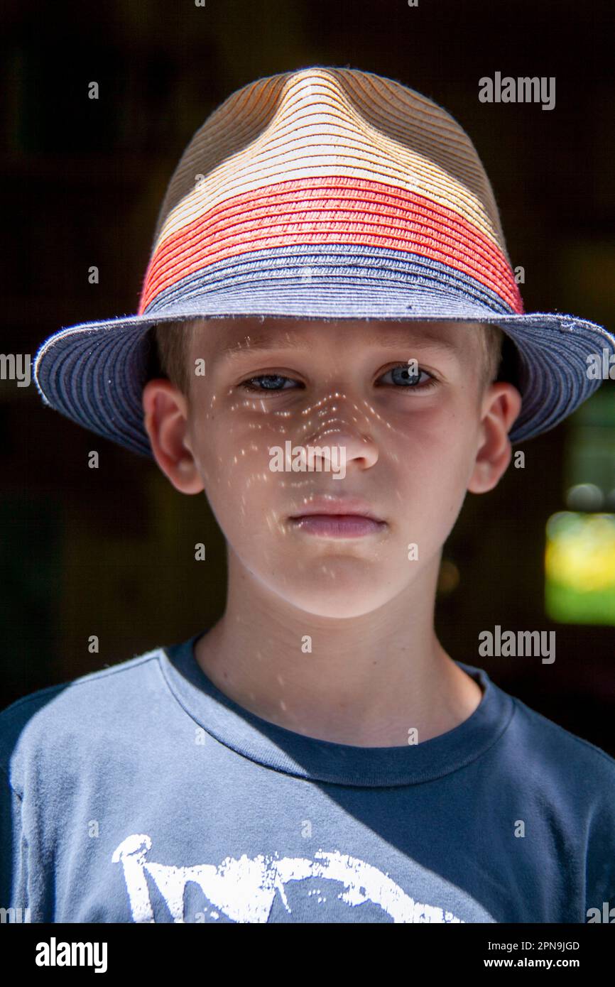 Head and shoulders portrait of young boy wearing straw hat Stock Photo