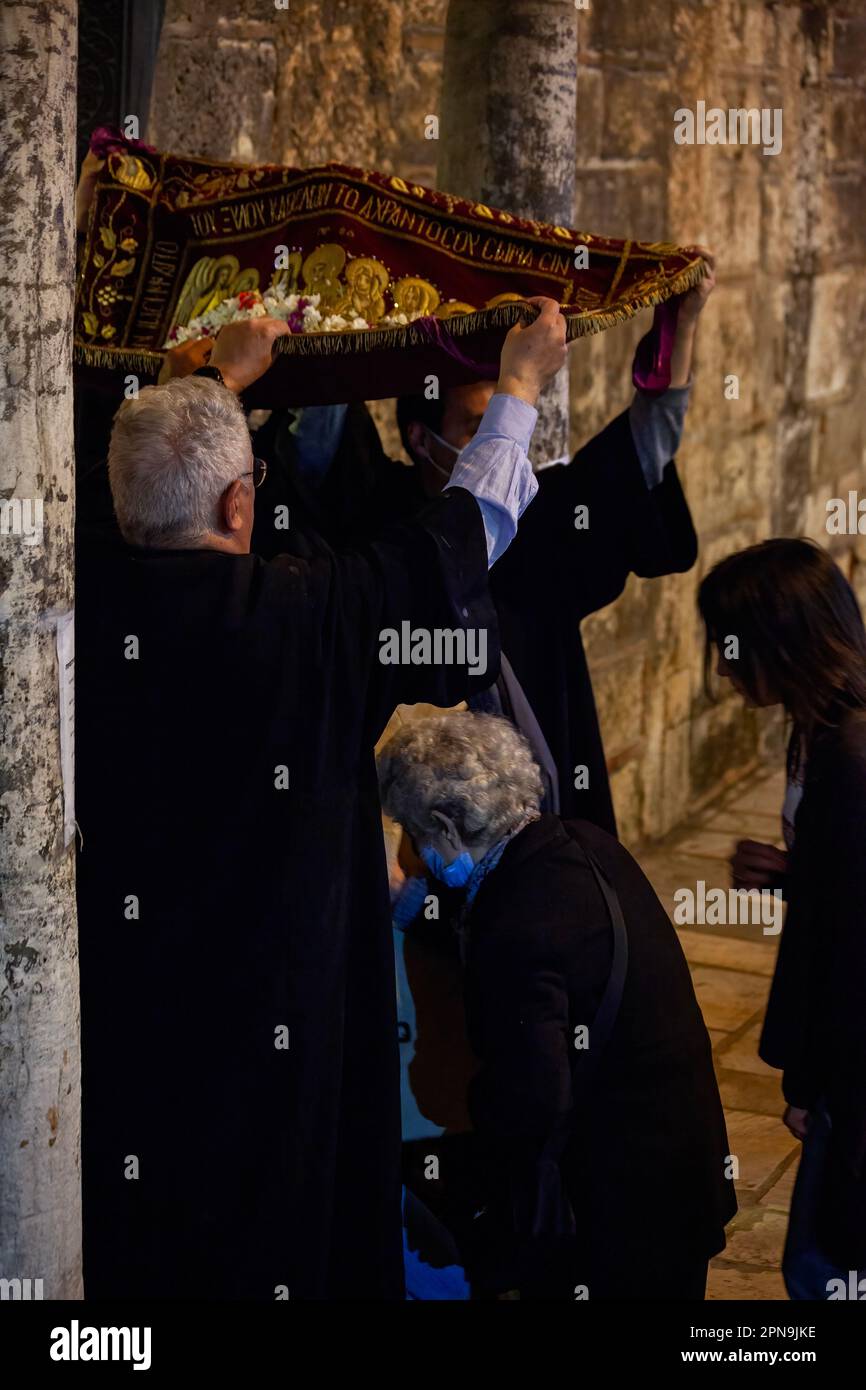 Believers come to the byzantine church of Panagia Kapnikarea during the Epitaph (Good Friday), passing below a carpet that represents the Epitaph. Stock Photo