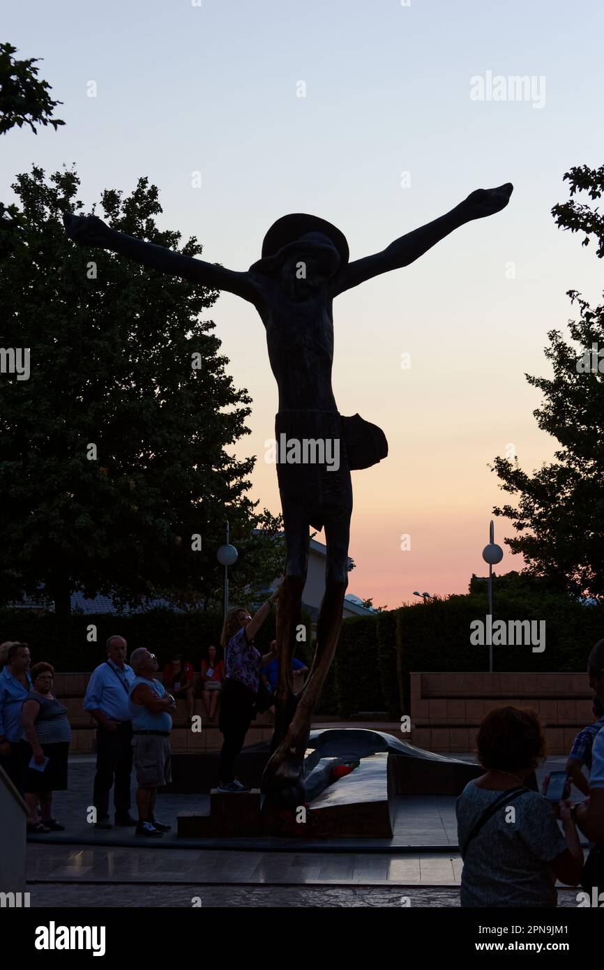 People venerating the statue of the Risen Christ in Medjugorje. The statue miraculously weeps drops of fluid from Jesus' right knee. Stock Photo