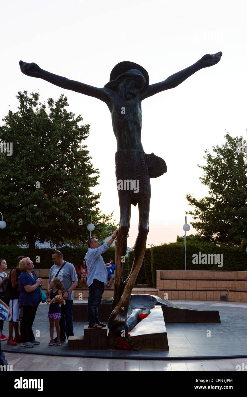 People venerating the statue of the Risen Christ in Medjugorje. The statue miraculously weeps drops of fluid from Jesus' right knee. Stock Photo