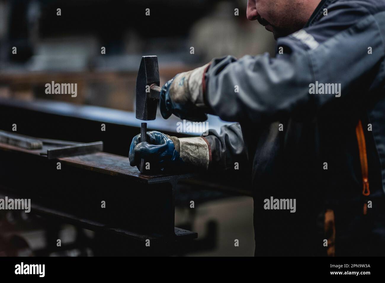 A metal worker marks a drill hole on a steel girder, picture taken in a