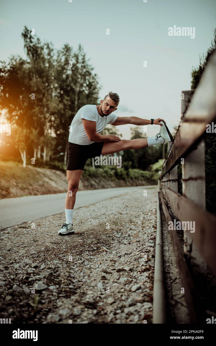 Athlete performing leg stretching exercises after a run in a natural