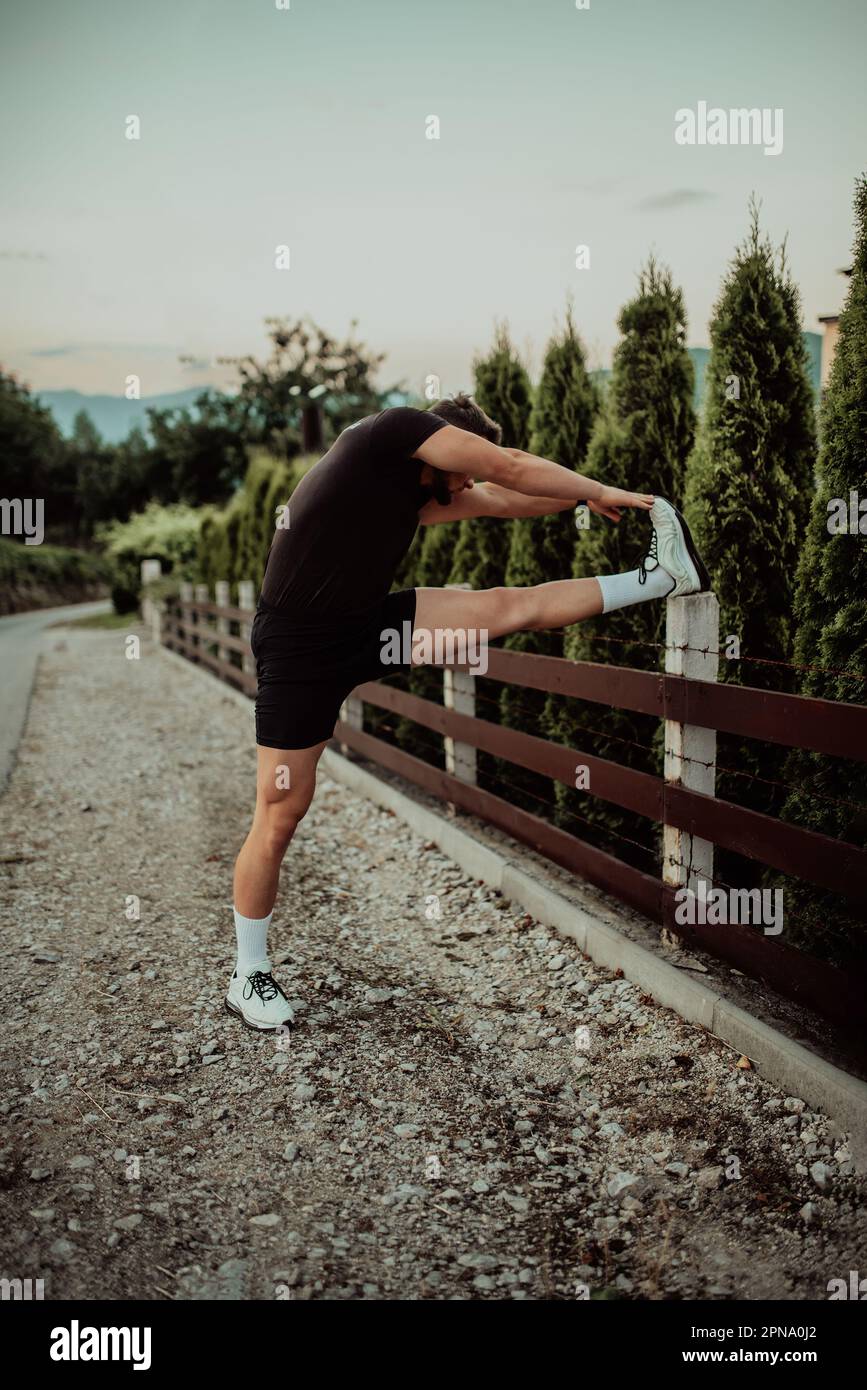 Athlete performing leg stretching exercises after a run in a natural