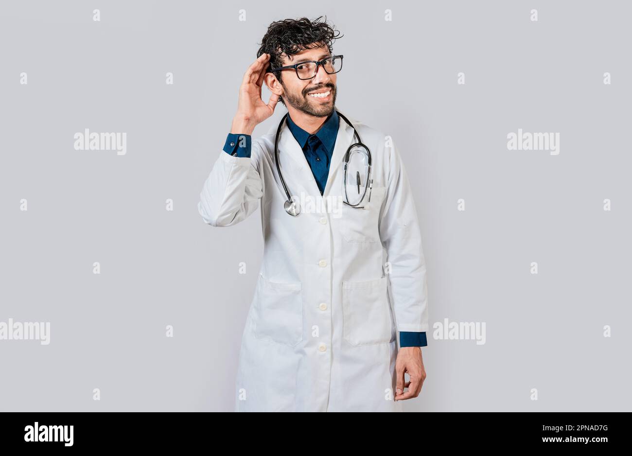 Smiling doctor listening to a rumor. Young doctor smiling with hand over ear isolated, Smiling doctor extending hand isolated Stock Photo