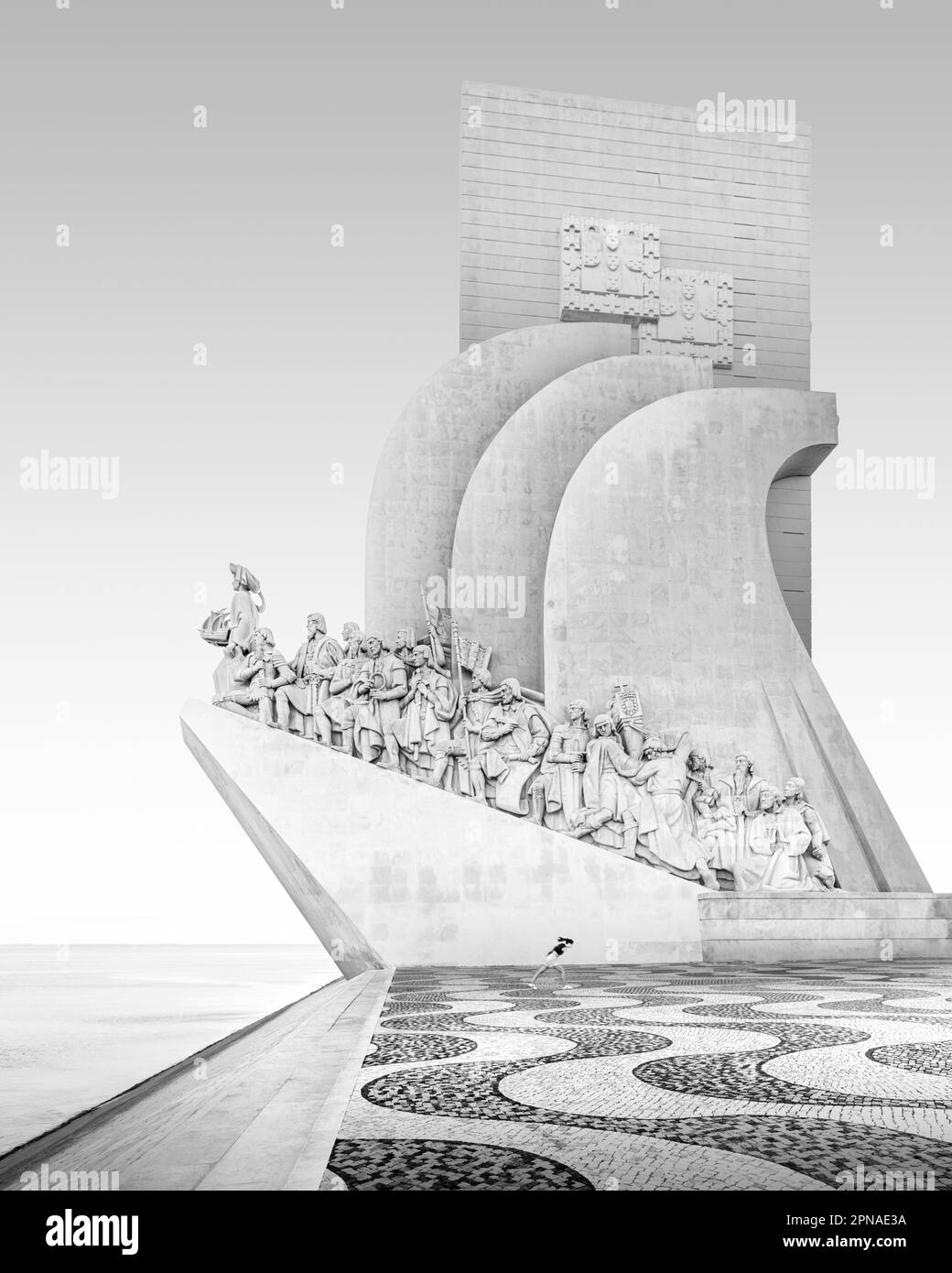 Black and white photograph of a running girl at the seafarers' monument Padrao dos Descobrimentos on the river Tagus in Lisbon, Portugal Stock Photo