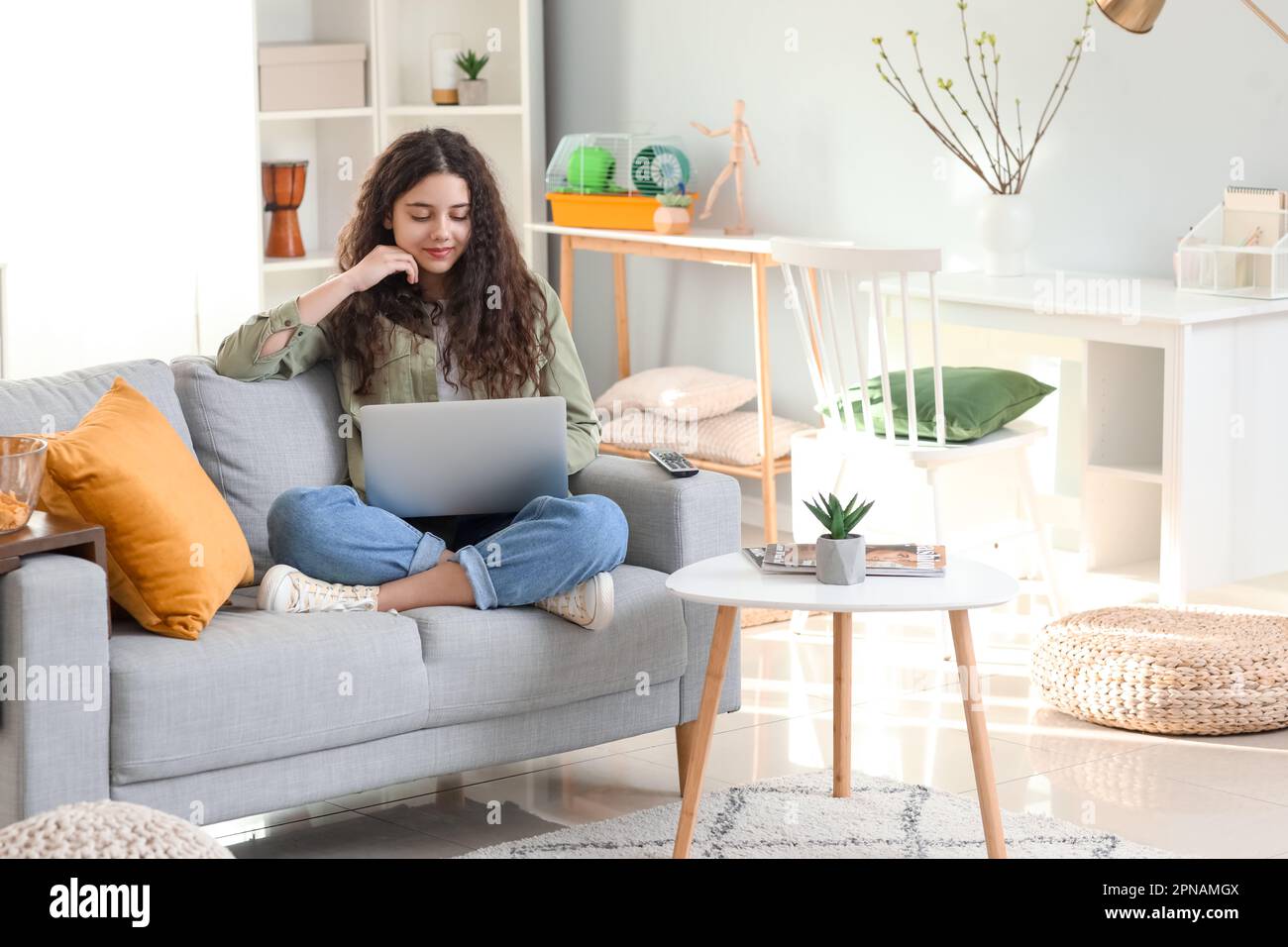 Teenage girl using laptop on sofa at home Stock Photo - Alamy
