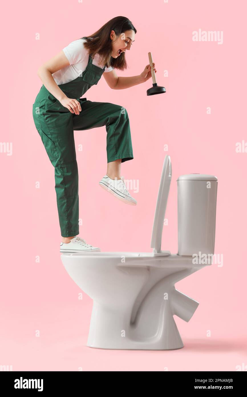 Funny female plumber with plunger and toilet bowl on pink background