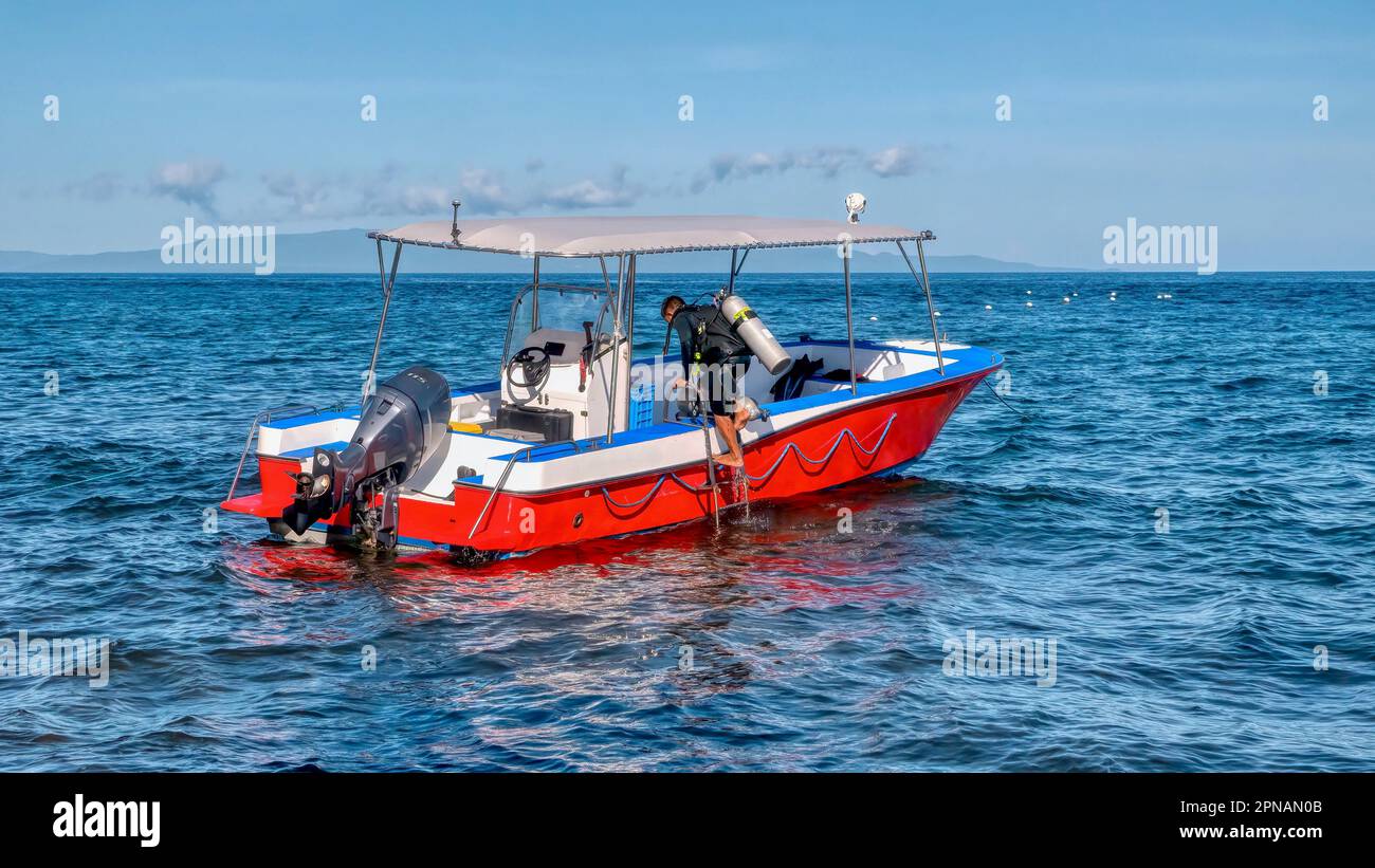 An unidentied resort boatman loads air tanks into the boat in preparation for the next group scuba dive, in the Philippines. Stock Photo