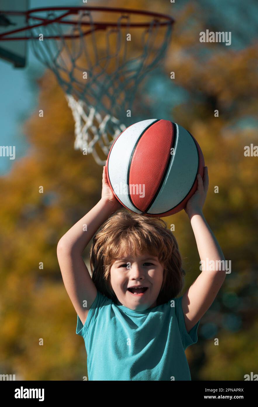 Cute smiling boy plays basketball. Active kids enjoying outdoor game