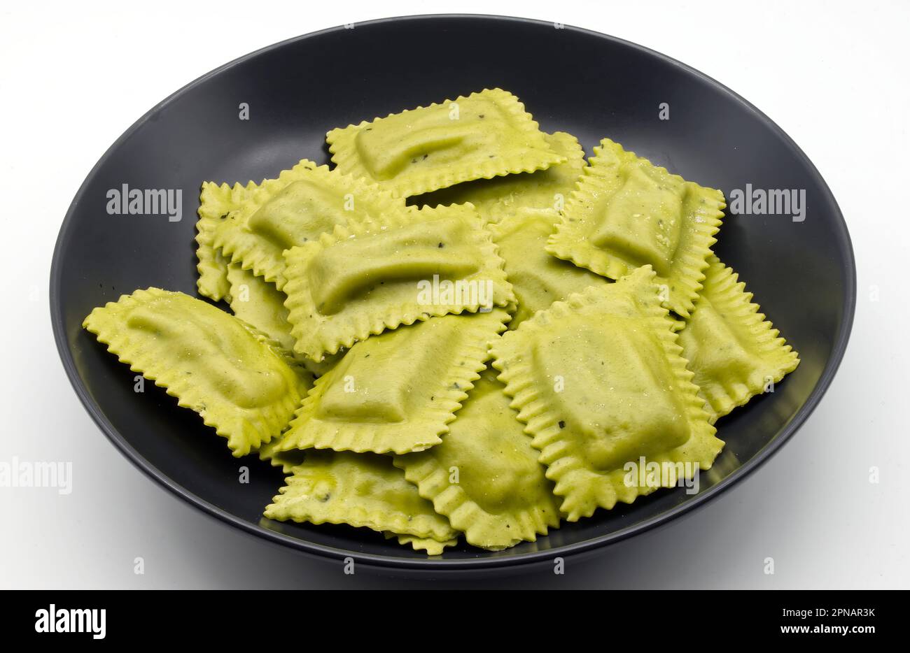 Raw Italian Tortelli al radicchio in a black dish isolated on white background. Stock Photo