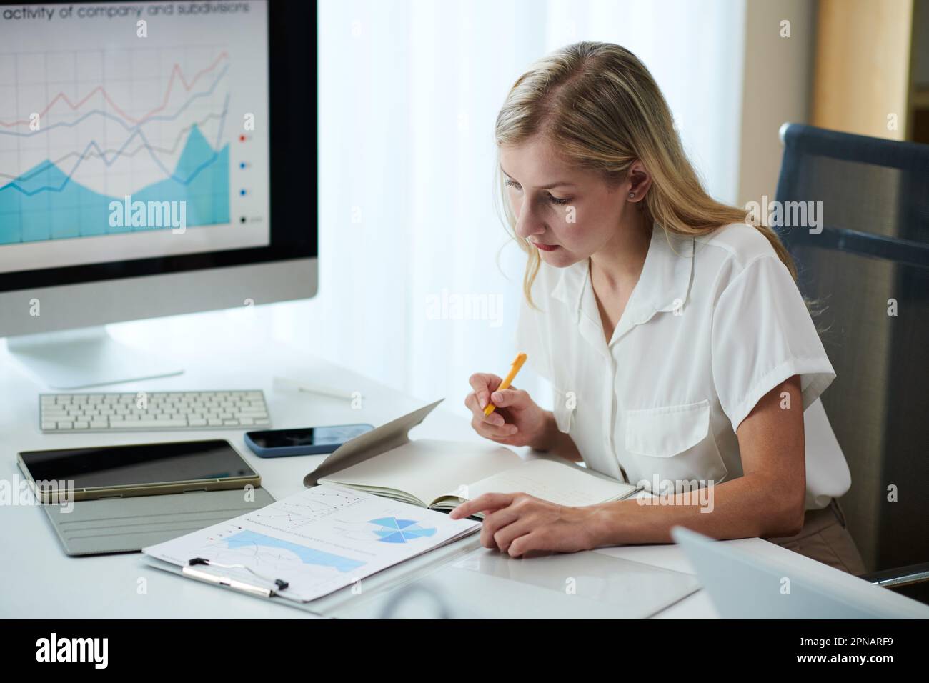 Female entrepreneur analyzing report and taking notes in planner Stock ...